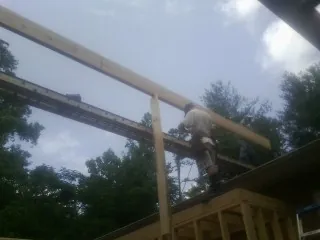 Carpenter setting a ridge beam over a new addition frame — Ice Dam Removal by Roofing Brothers in Woolstock