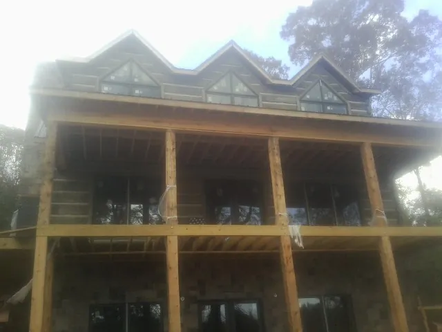 Dormers and porch framing on a large log home under construction — Roof Coating work by our crew in Woolstock