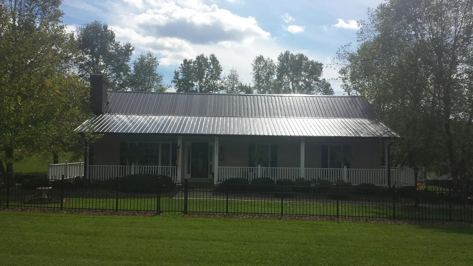 Gray metal roof on a brick ranch with a full width front porch — Gutter Guard Installation work by our crew in Woolstock